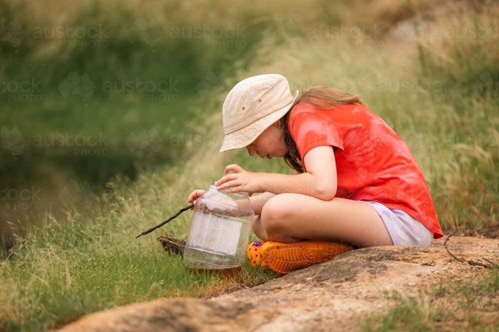 Girl catching tadpoles. Outdoor nature activity. - Australian Stock Image