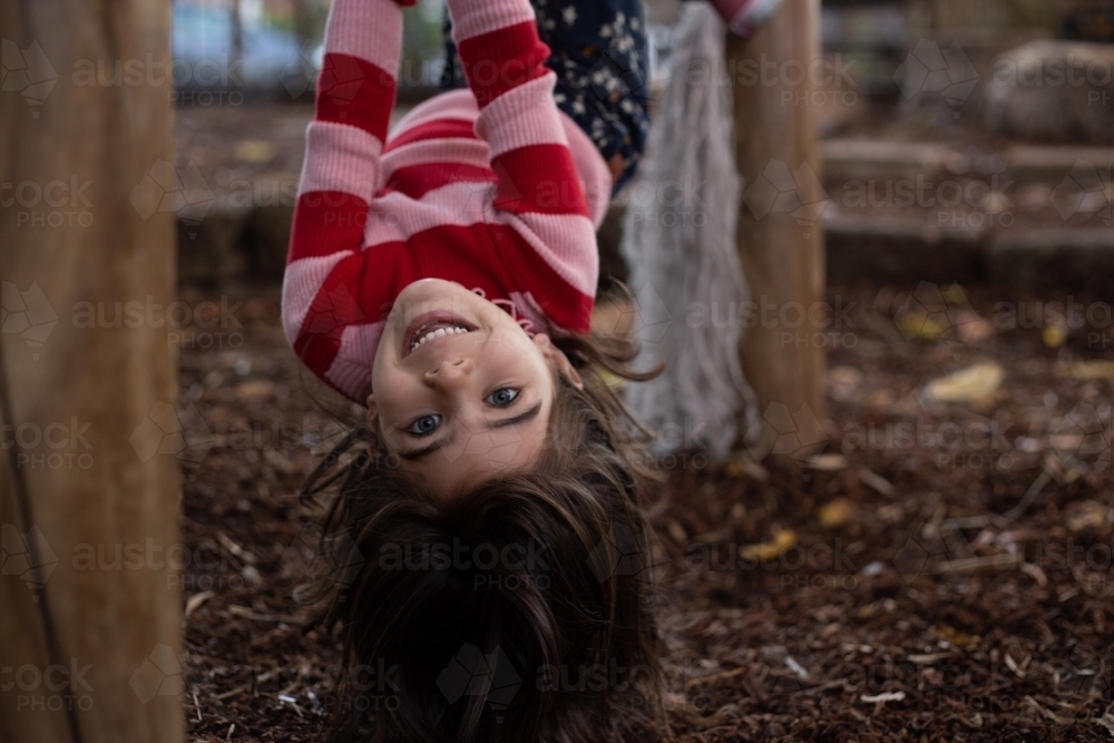 Girl child upside down on play equipment - Australian Stock Image