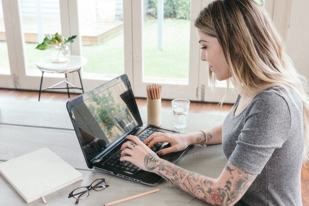 Girl concentrating on working on a laptop at home - Australian Stock Image