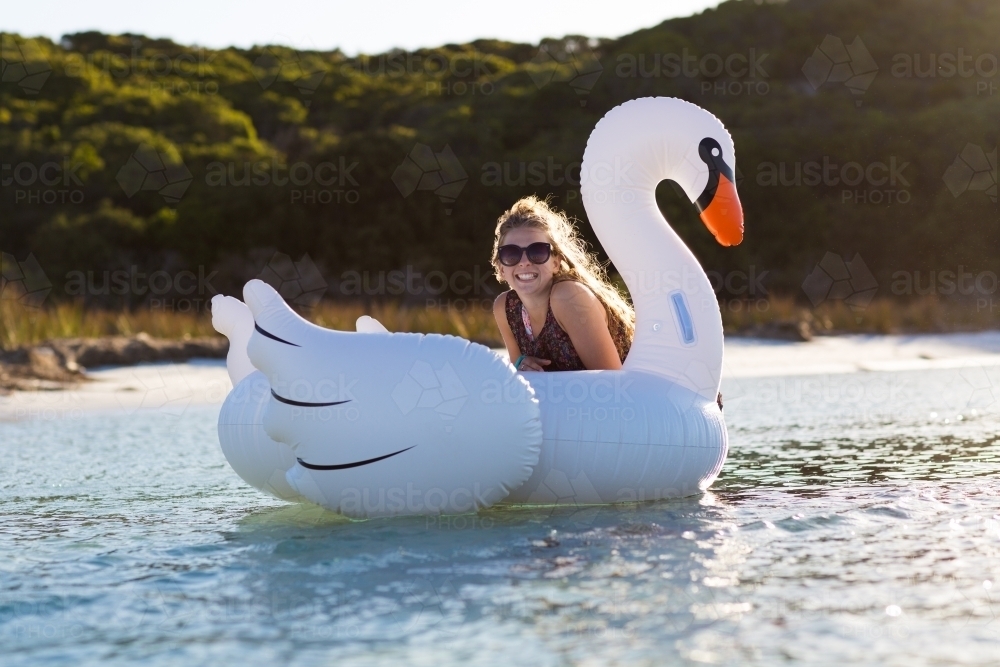 Girl cooling off in water with giant inflatable swan - Australian Stock Image