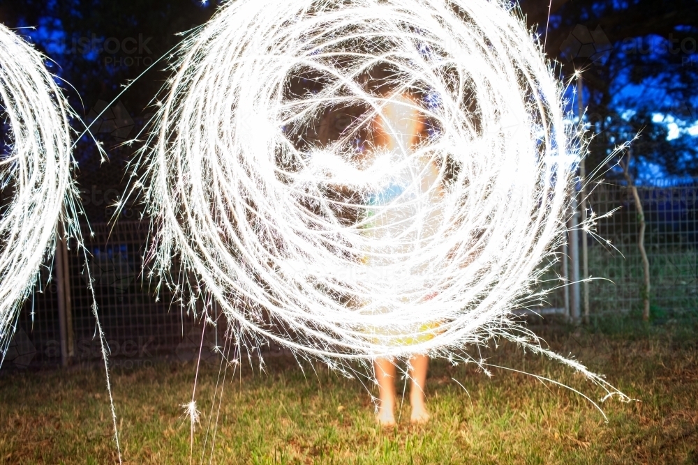 Girl creating a circle shape with a sparkler at night - Australian Stock Image