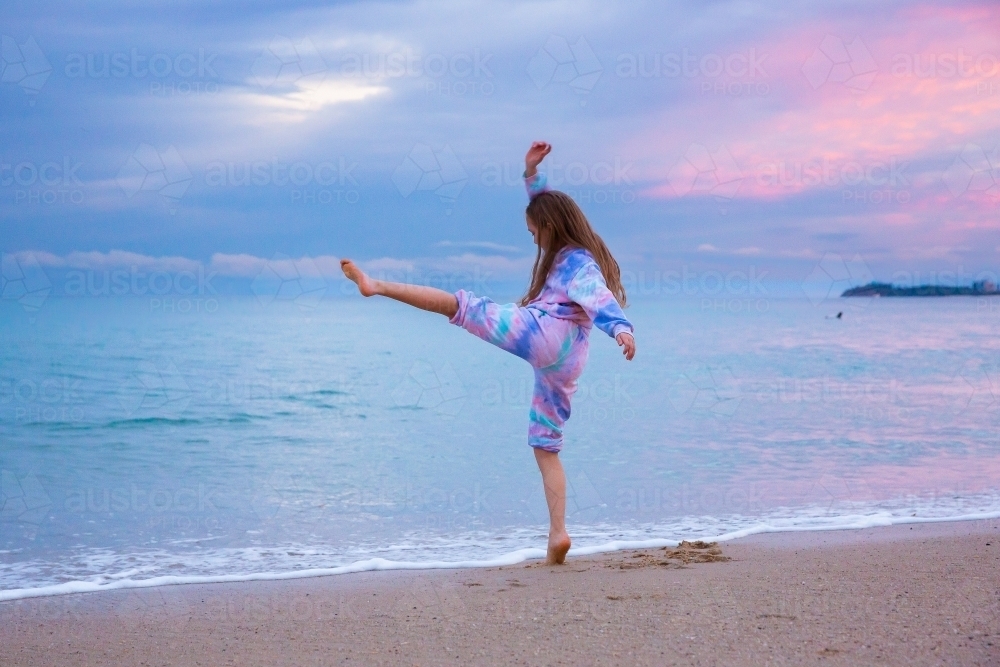 girl dancing at the beach at dusk - Australian Stock Image