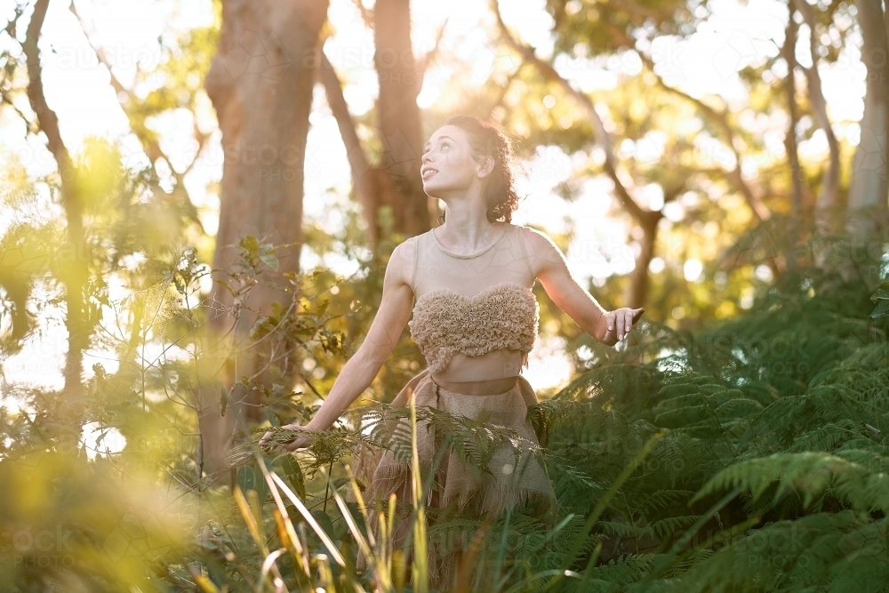 girl dancing in the forest looking in to the sunlight - Australian Stock Image