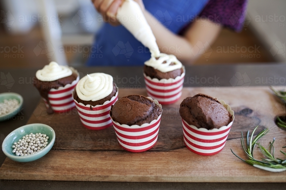 Girl decorating cupcakes in kitchen at home - Australian Stock Image