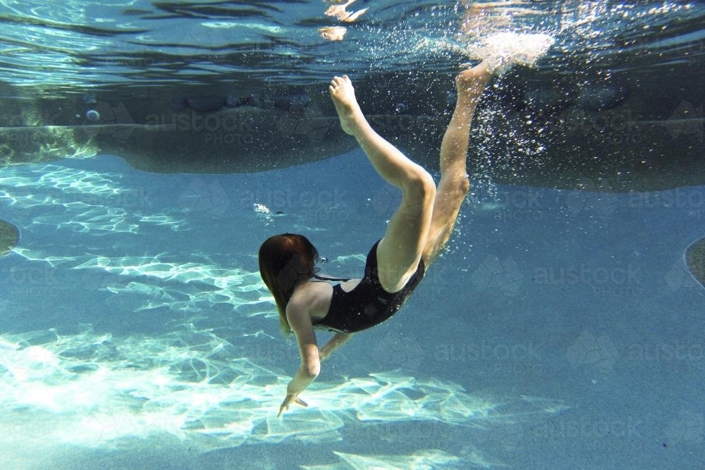 Girl diving underwater in a pool : Austockphoto Girl diving underwater in a pool - Australian Stock Image