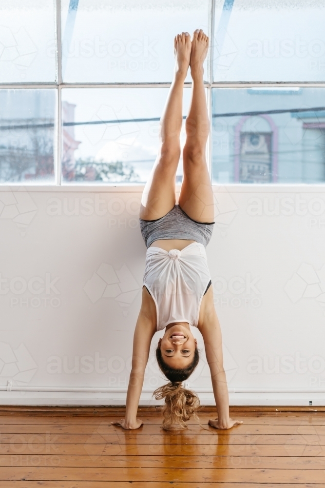 Girl doing a handstand in workout gear - Australian Stock Image