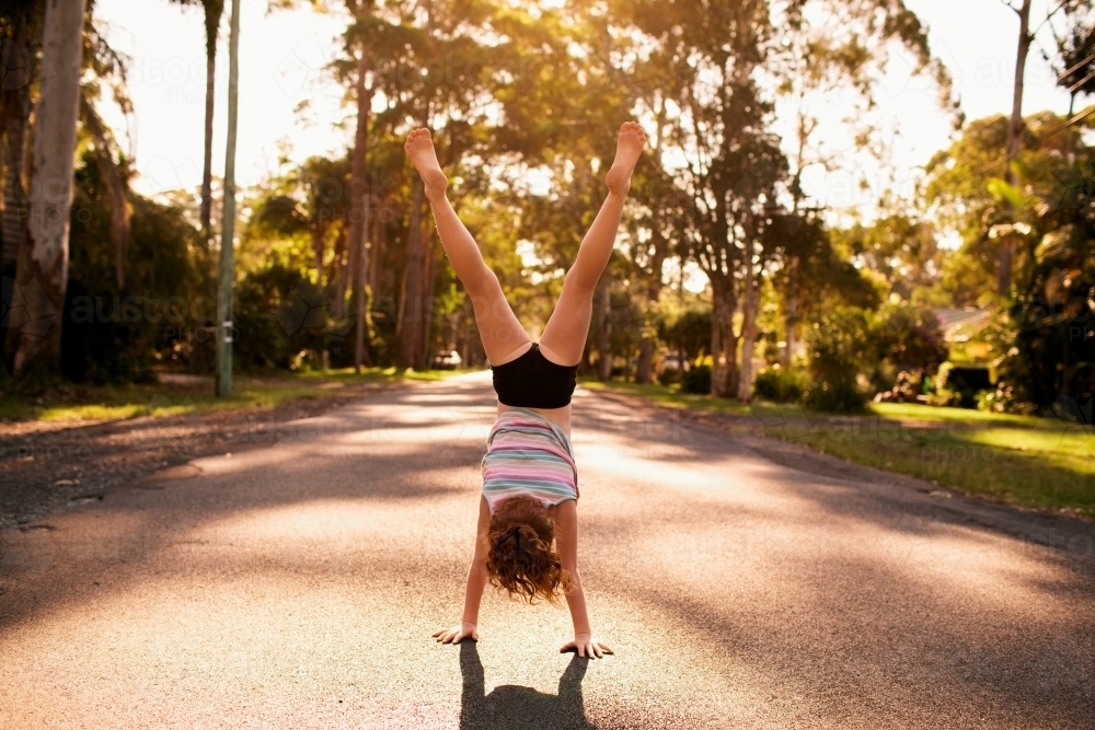 Girl doing a handstand on a road - Australian Stock Image