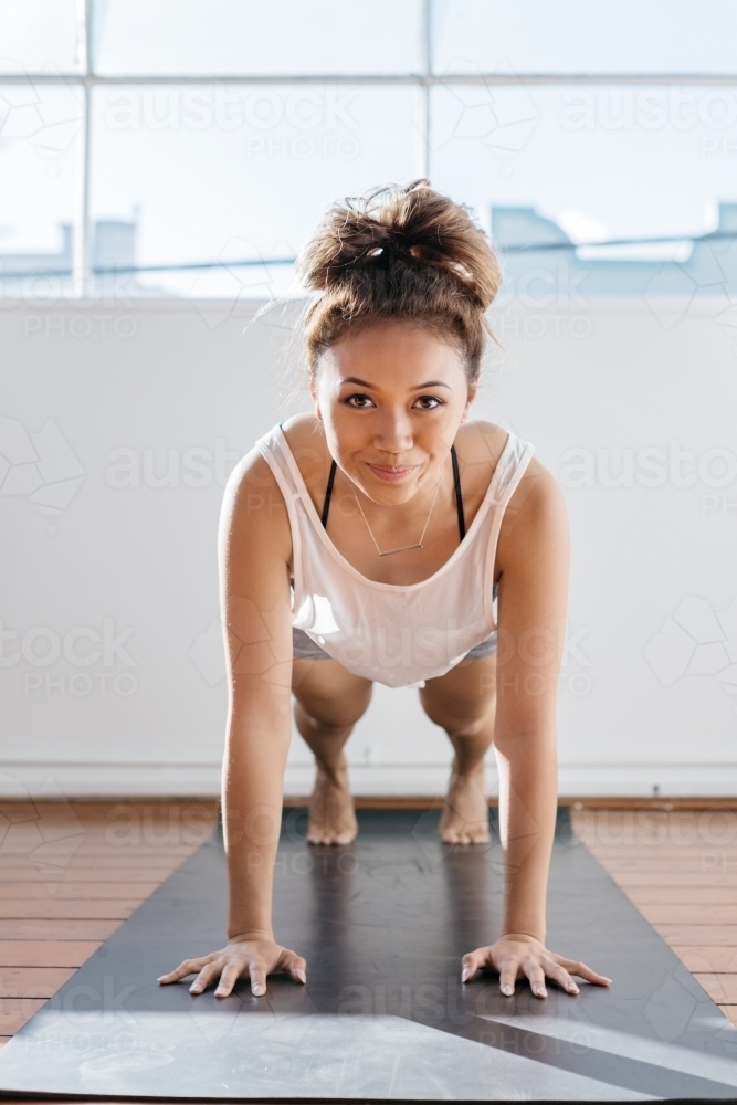 Girl doing a plank exercise at the gym staring at camera - Australian Stock Image