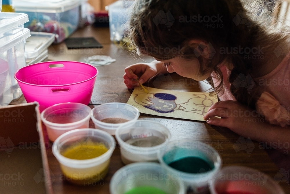 Girl doing craft at table in morning light - Australian Stock Image