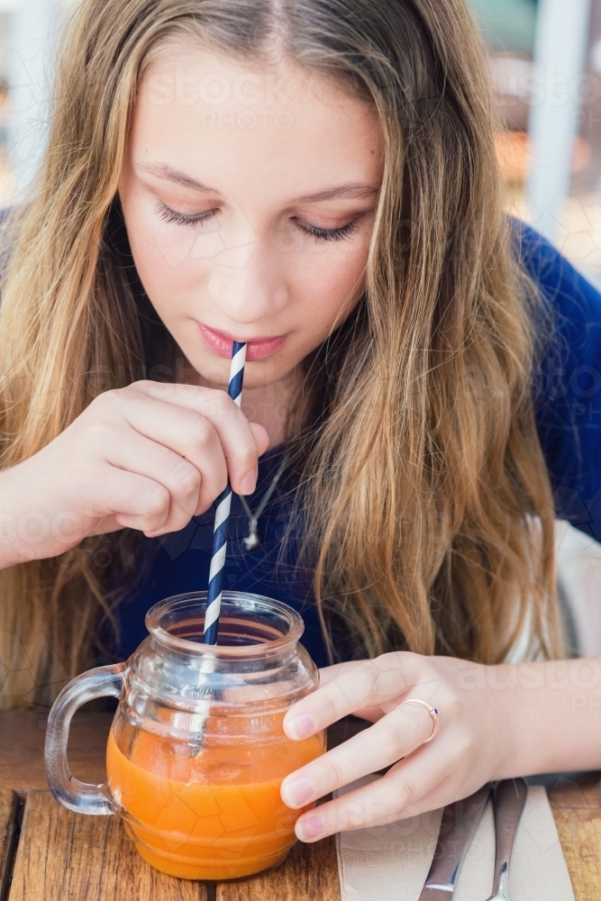 girl drinking juice at cafe - Australian Stock Image
