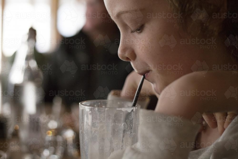 Girl drinks milkshake through a straw - Australian Stock Image