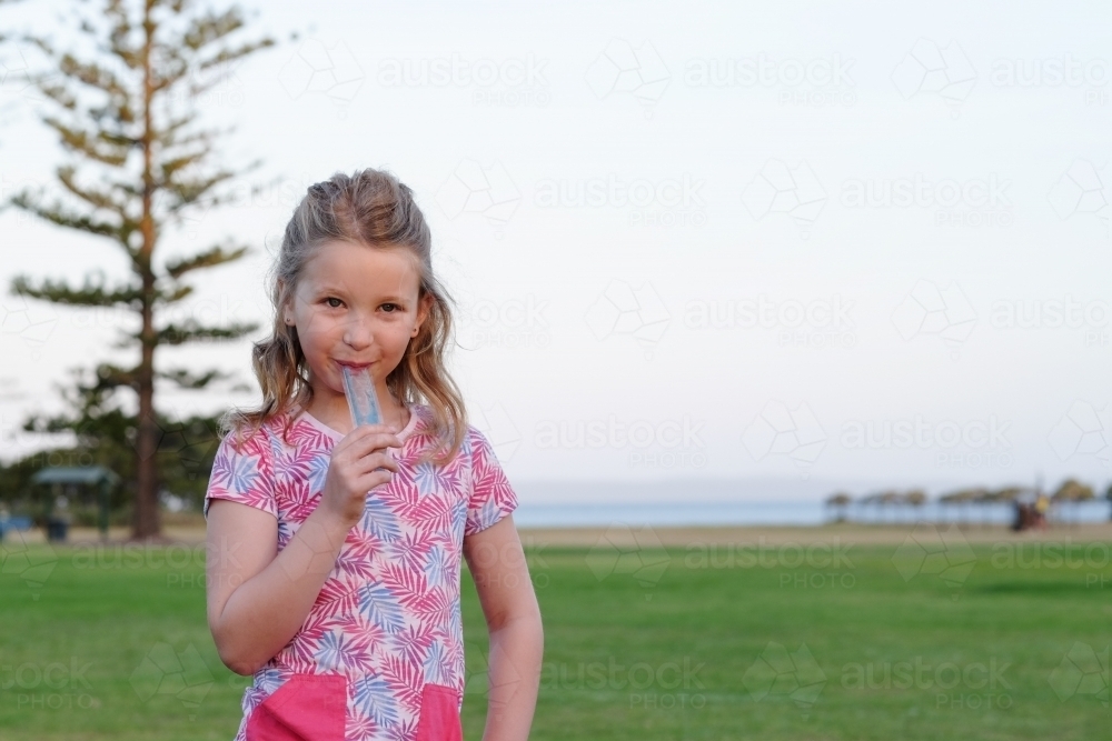 Girl eating an ice block in the park - Australian Stock Image