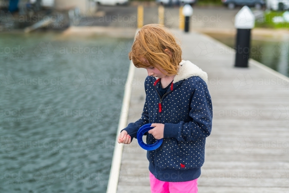 girl fishing with a hand reel from a wooden jetty - Australian Stock Image