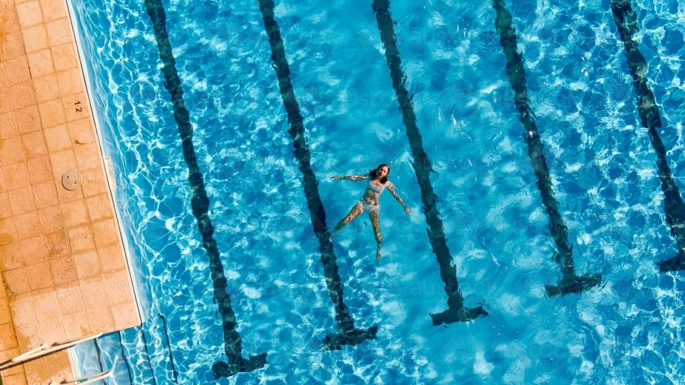 Girl floating in swimming pool - Australian Stock Image