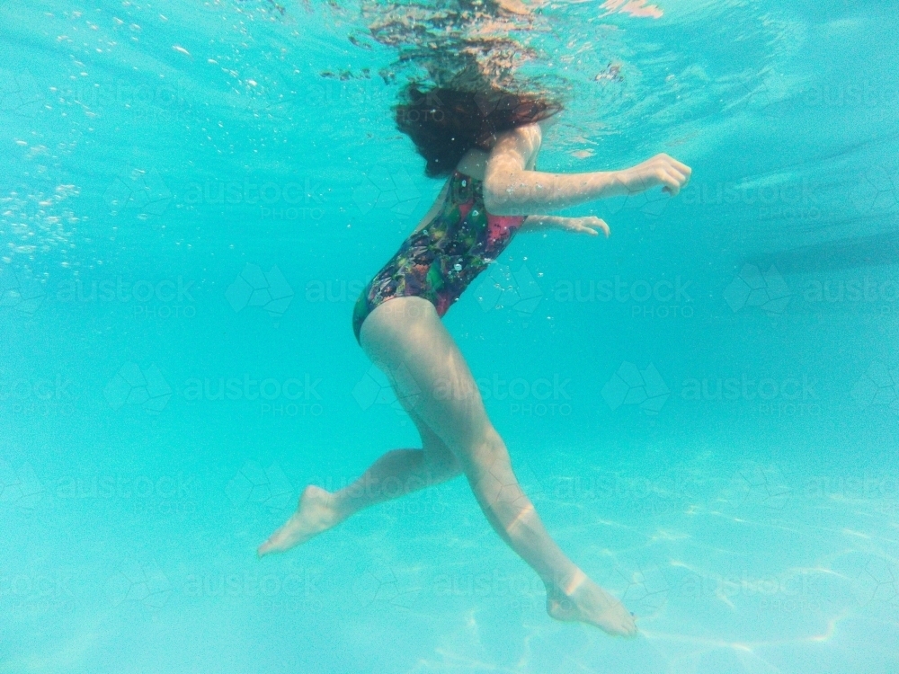 Girl floating underwater in a pool - Australian Stock Image
