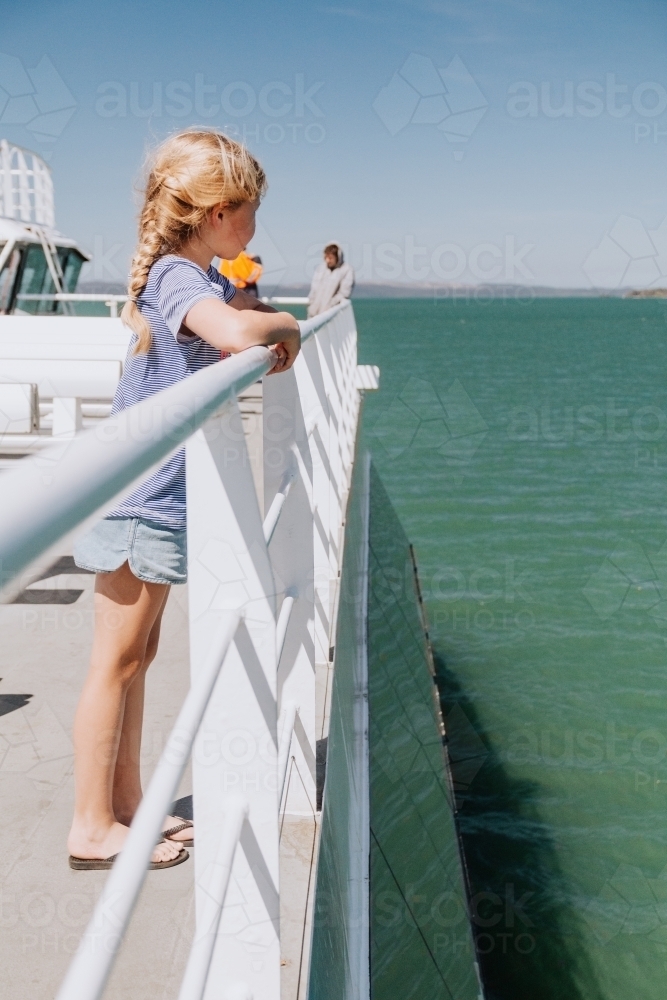 Girl gazing out to the ocean as she crosses on ferry - Australian Stock Image