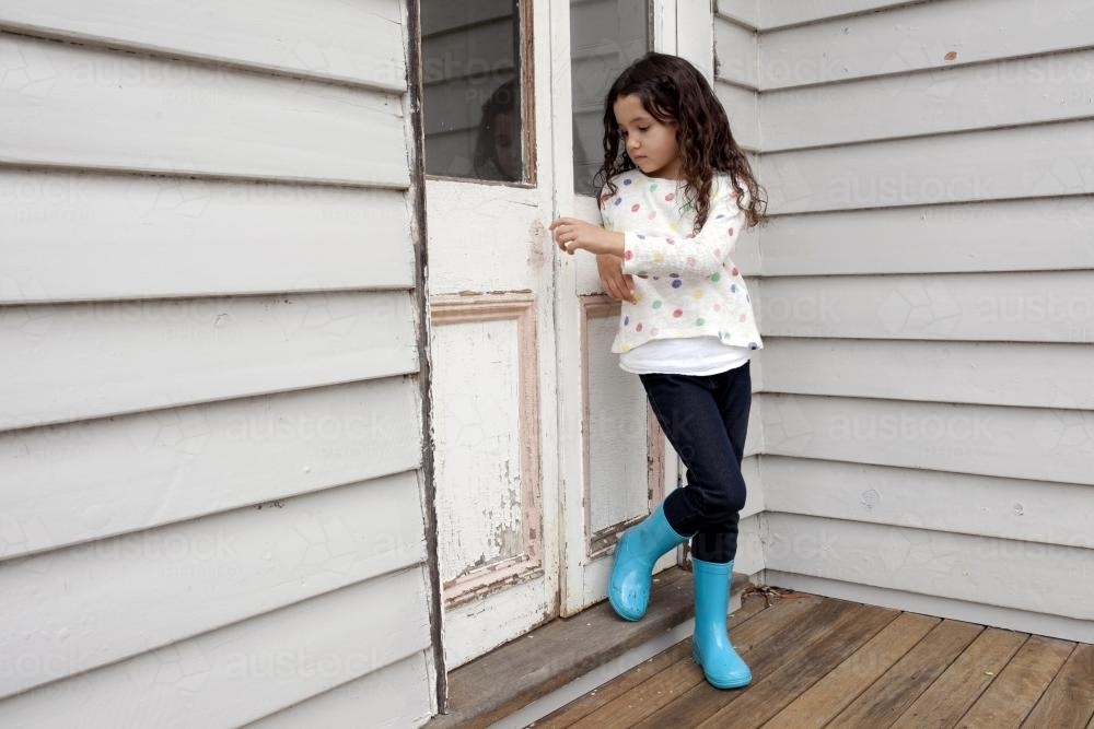 Girl heading outside with blue gumboots - Australian Stock Image