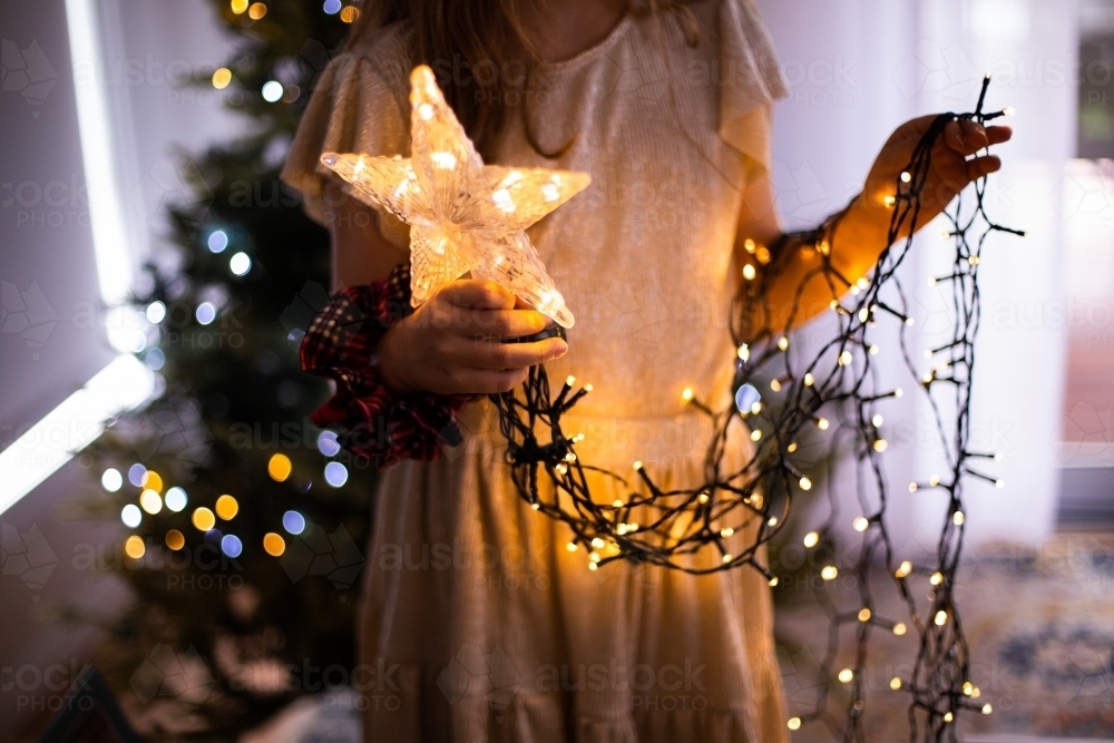 girl holding a light up star with trailing strings of lights - Australian Stock Image