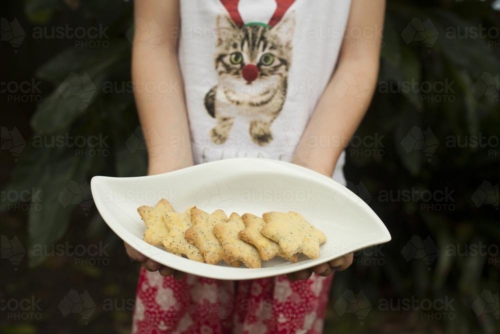 Girl holding a plate of Christmas biscuits - Australian Stock Image