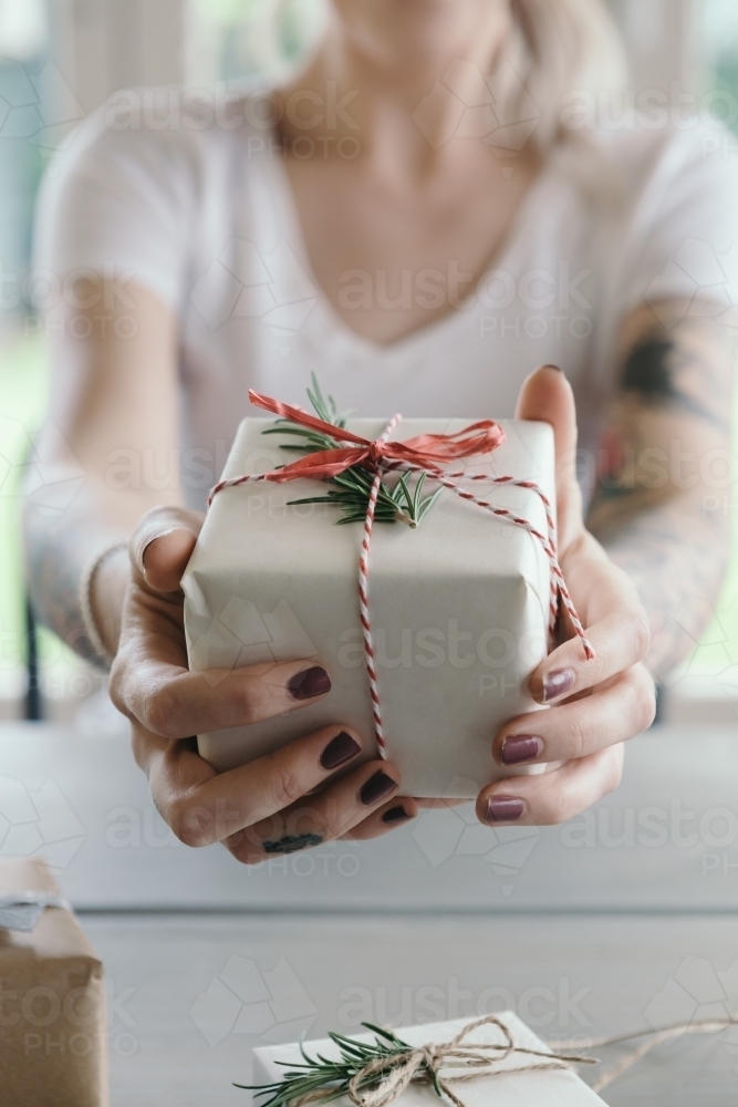 Girl holding gift wrapped christmas present to camera - Australian Stock Image