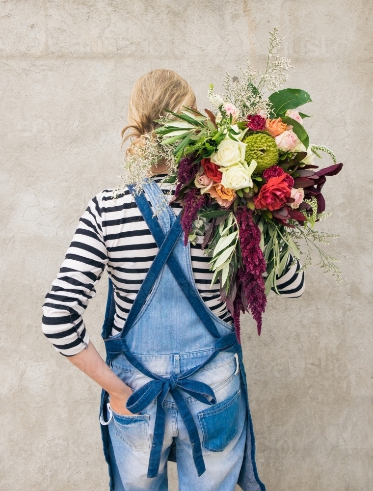 Girl holding huge floral arrangement over shoulder - Australian Stock Image