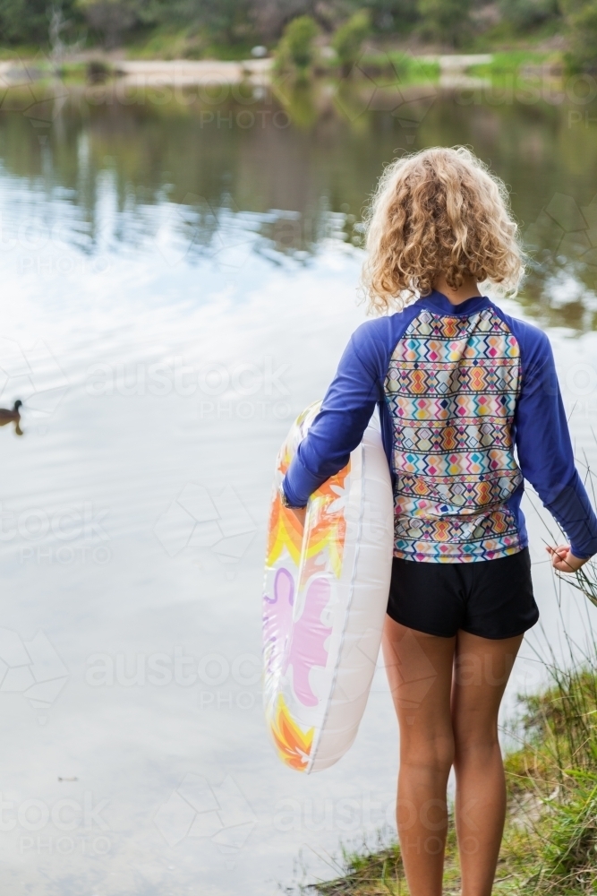 Girl holding swim ring beside lake - Australian Stock Image