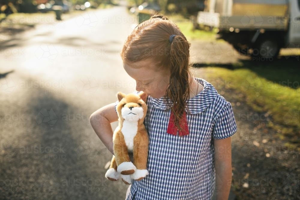 Girl hugging a toy dog on the street - Australian Stock Image