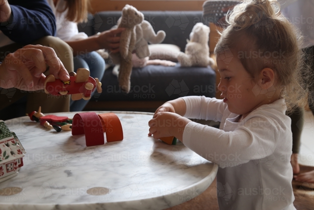 Girl in lounge room playing with toys on coffee table - Australian Stock Image