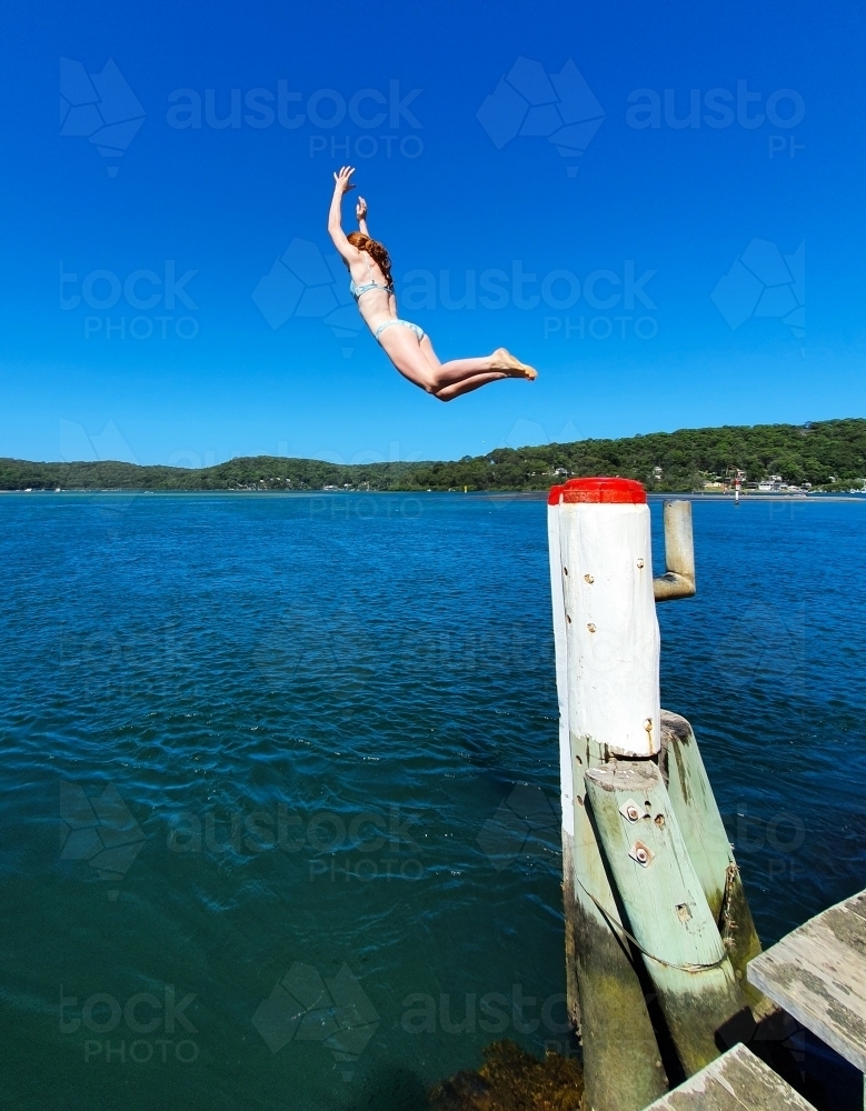 Girl jumping off a wharf - Australian Stock Image