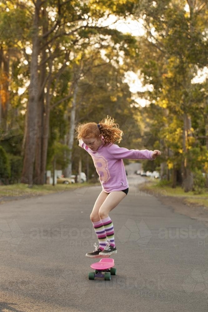 Girl jumping on a skateboard in the street - Australian Stock Image