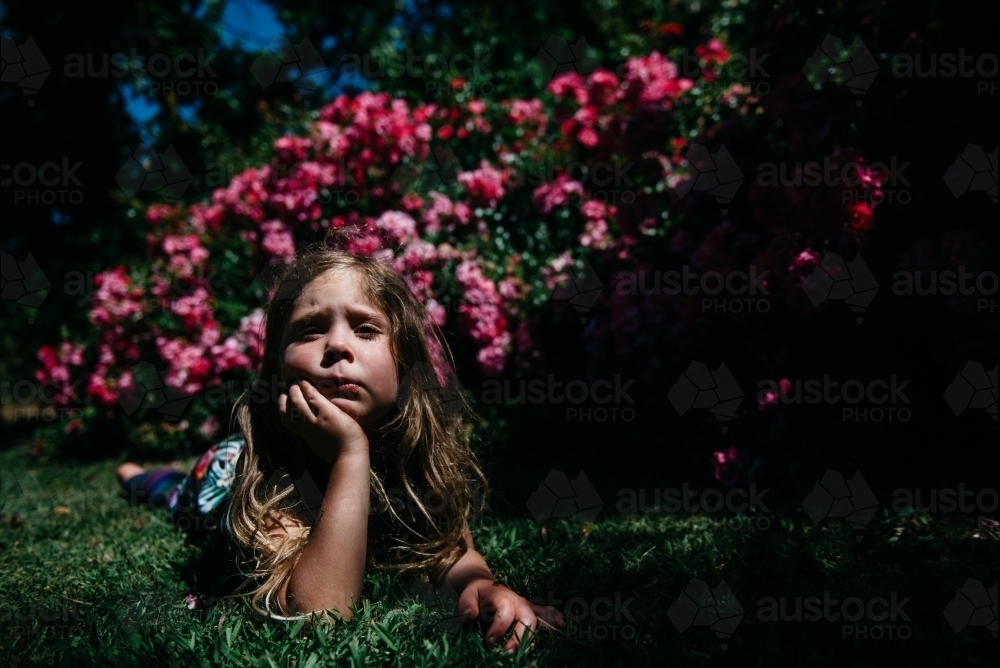 Girl laying in garden, resting her chin in her hand - Australian Stock Image