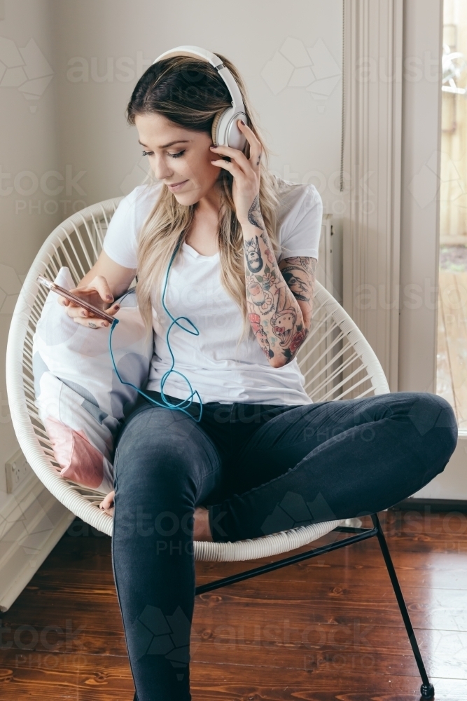 Girl listening to music on her smartphone at home - Australian Stock Image