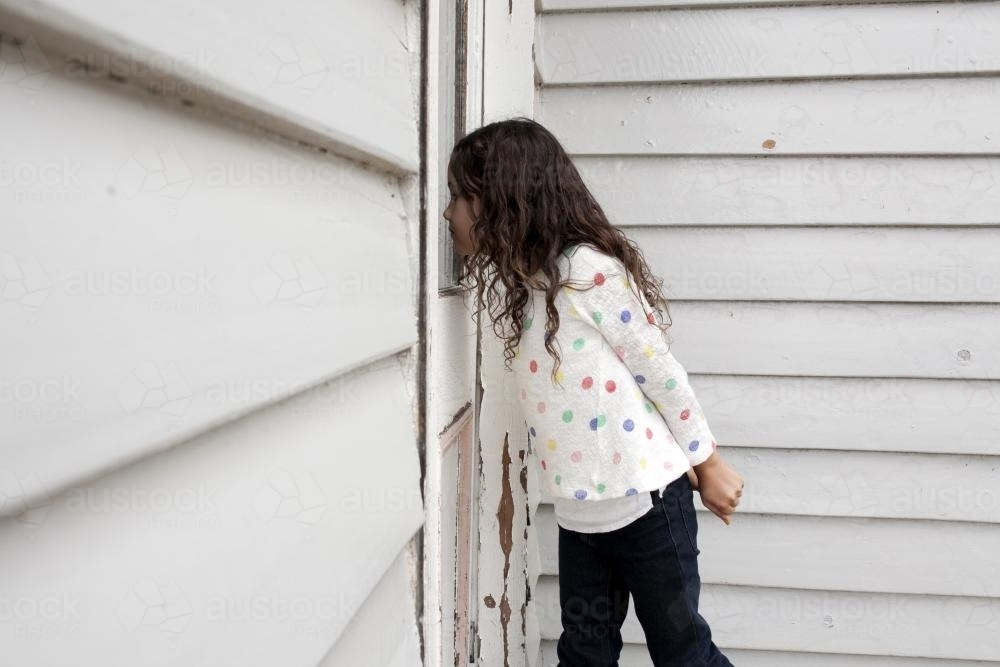 Girl looking into house from outside - Australian Stock Image