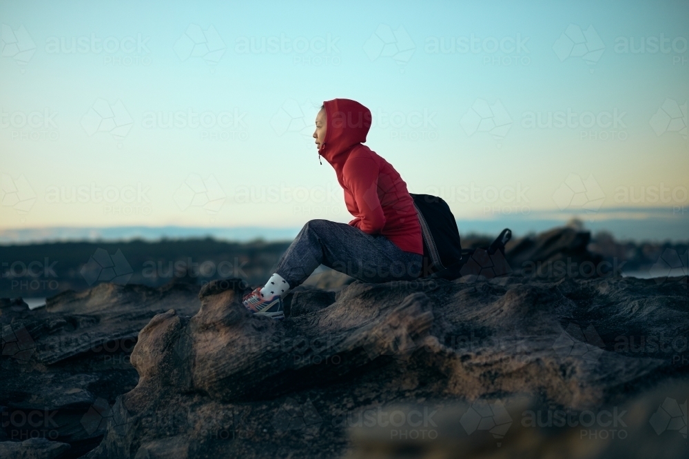 Girl looking out to ocean in winter with active wear - Australian Stock Image