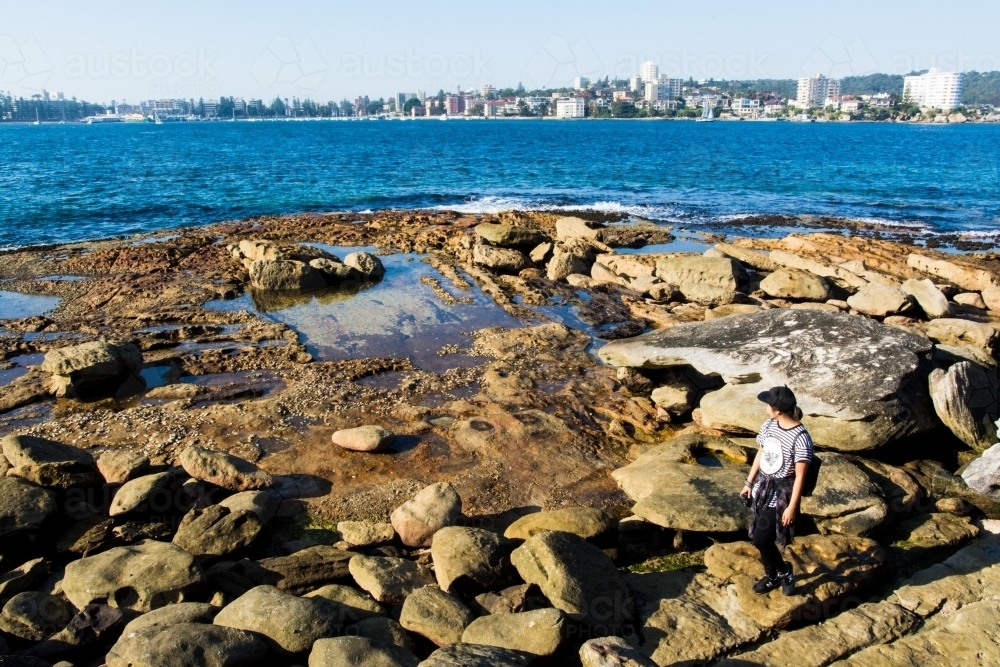 Girl looking out to sea with city skyline in the background - Australian Stock Image