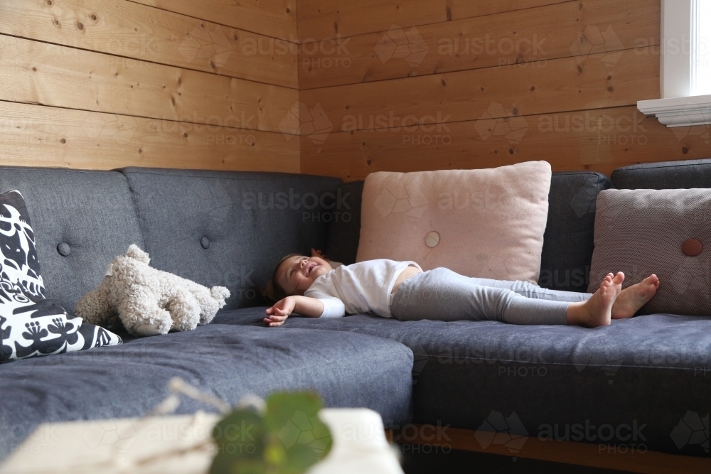 Girl lying on lounge laughing : Austockphoto Girl lying on lounge laughing - Australian Stock Image
