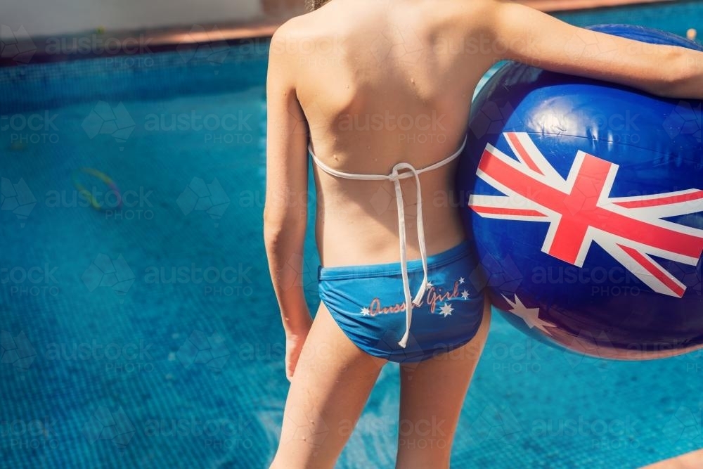 girl on the side of a swimming pool with an Australian flag ball - Australian Stock Image