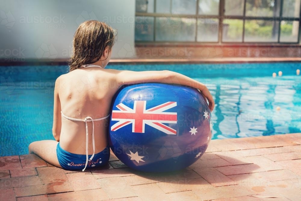 girl on the side of a swimming pool with an Australian flag ball - Australian Stock Image