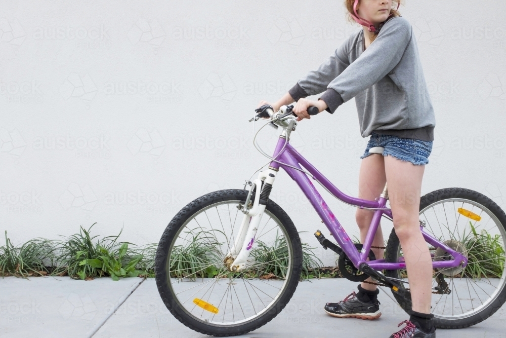 Girl pausing as she rides her bike along a suburban street - Australian Stock Image