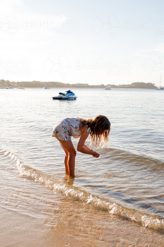 Girl picking up  something on the beach - Australian Stock Image