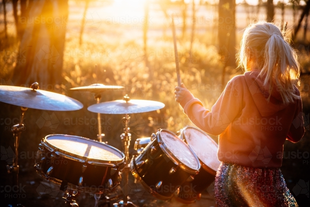 Girl playing drums outdoors in the sunshine - Australian Stock Image