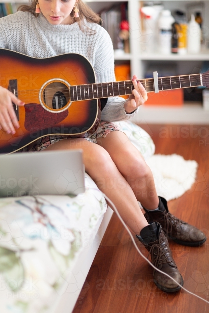 Girl playing guitar in her bedroom - Australian Stock Image