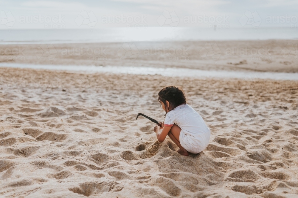 Girl playing in sand at the beach - Australian Stock Image