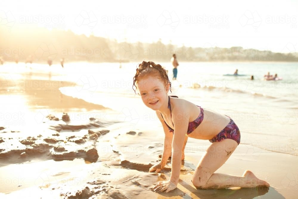 Girl playing in the sand at the beach - Australian Stock Image