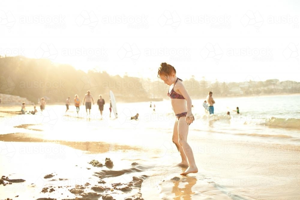 Girl playing in the sand at the beach - Australian Stock Image