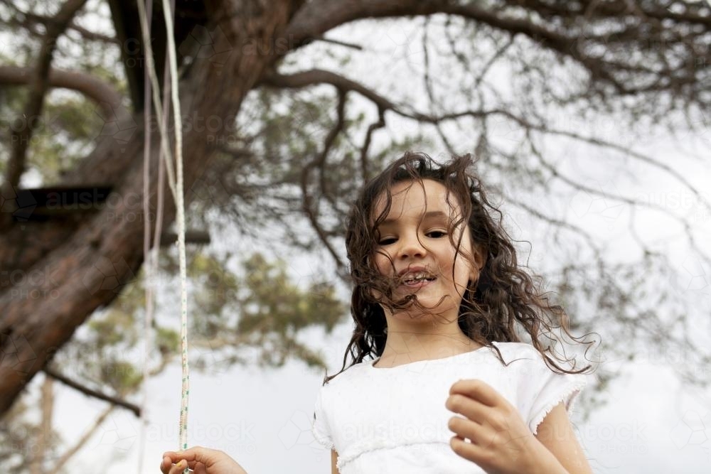 Girl playing outside with a rope swing - Australian Stock Image