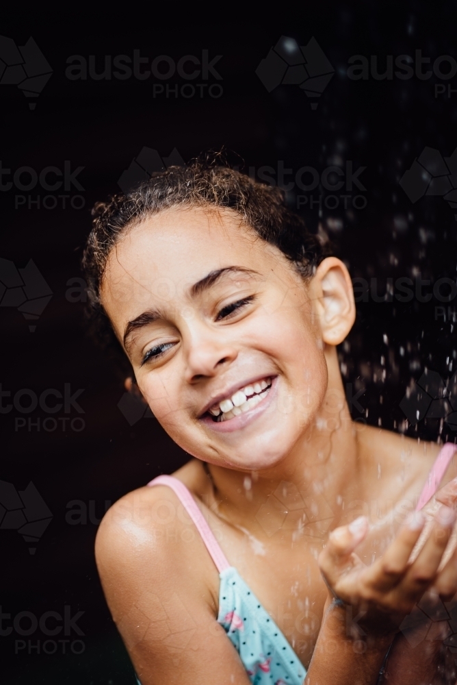 Girl playing under water splashes - Australian Stock Image