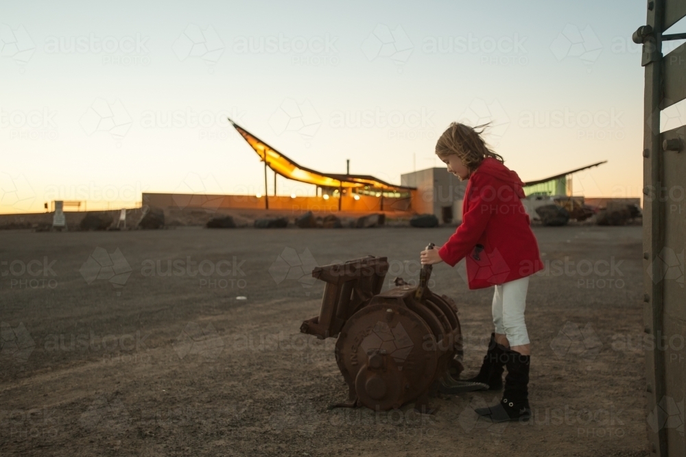 Girl playing with old mining tools at Broken Hills tourism center at dusk - Australian Stock Image