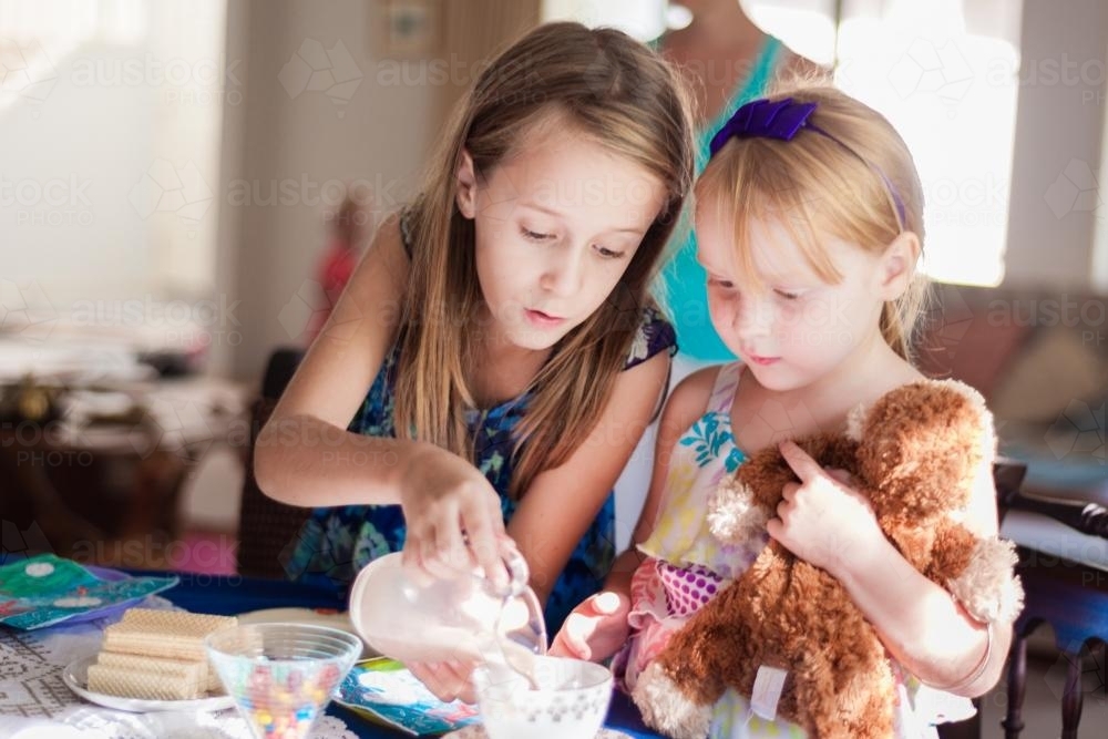 Girl pouring chocolate milk into a tea cup at a birthday party - Australian Stock Image