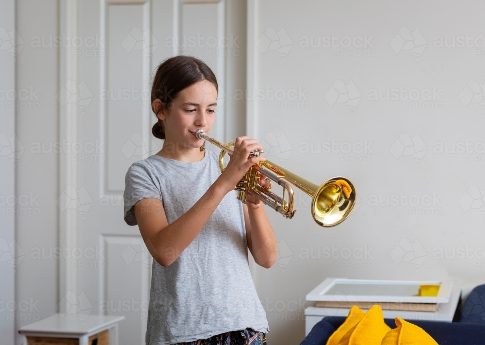 girl practising trumpet at home - Australian Stock Image